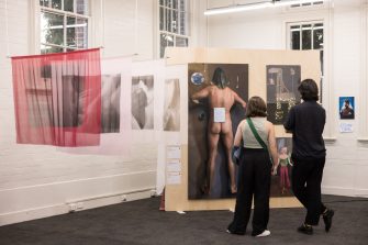 Two people standing in a gallery space, looking at the A&D Annual 2023 exhibition. 