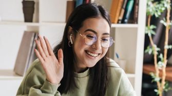 Happy young student waving at laptop