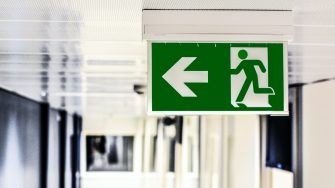 An close up of a green exit sign in a hallway