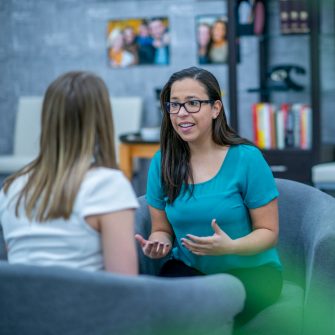 A woman in her early 30s explains something to a client who is sitting across from her. She looks passionate about what she is saying.