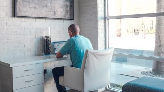 Young man working on laptop at desk with back to camera