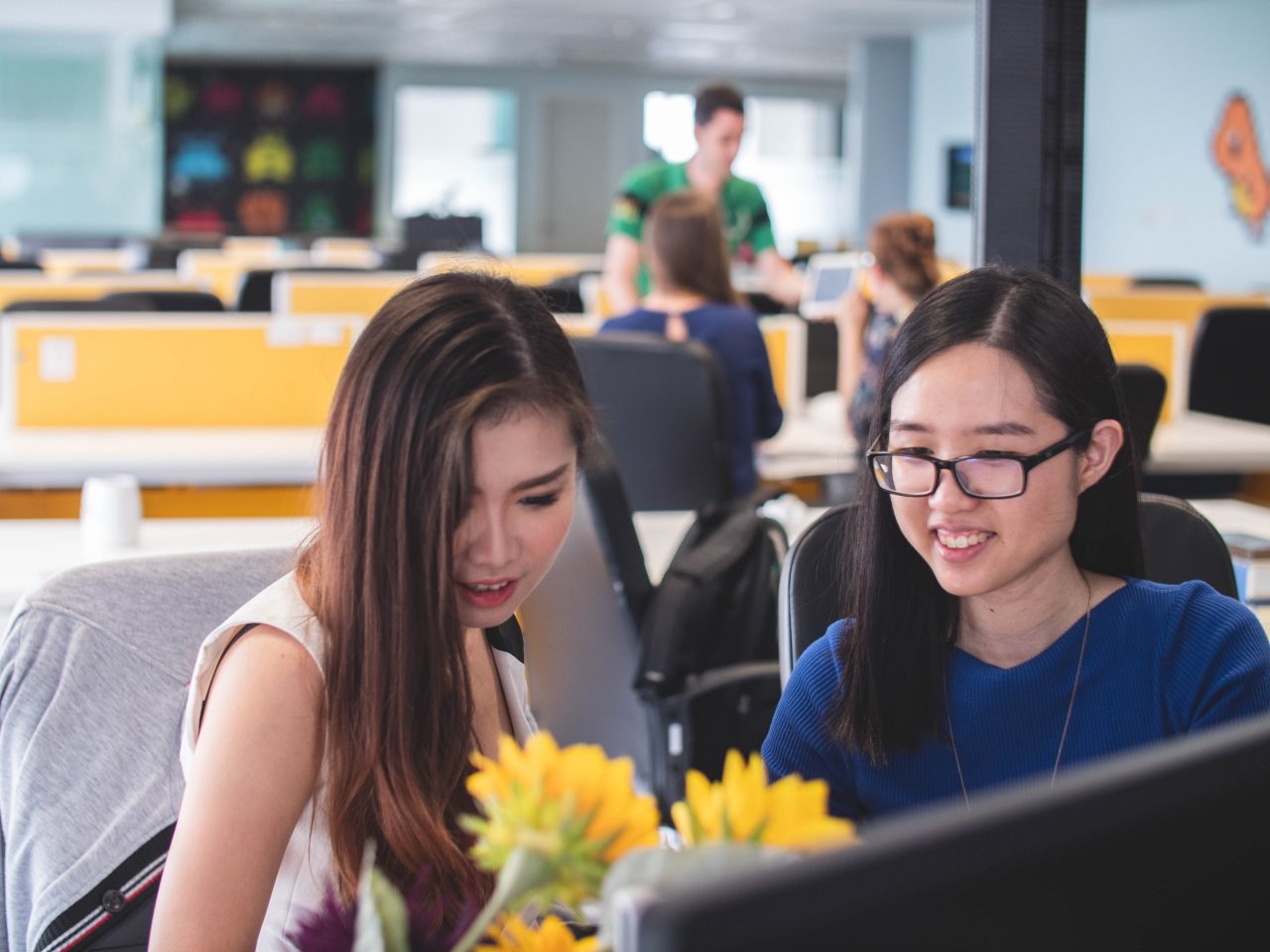 Two women smiling in front of a computer monitor