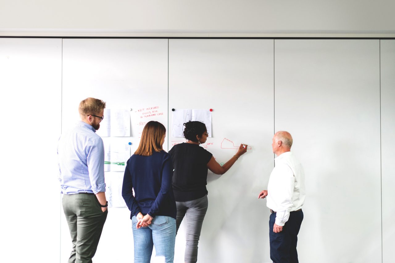 Group of people standing in front of whiteboard