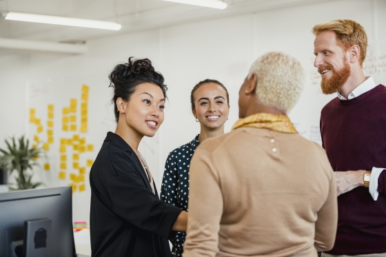 Colleagues standing in a small group discussing something while working at an office.