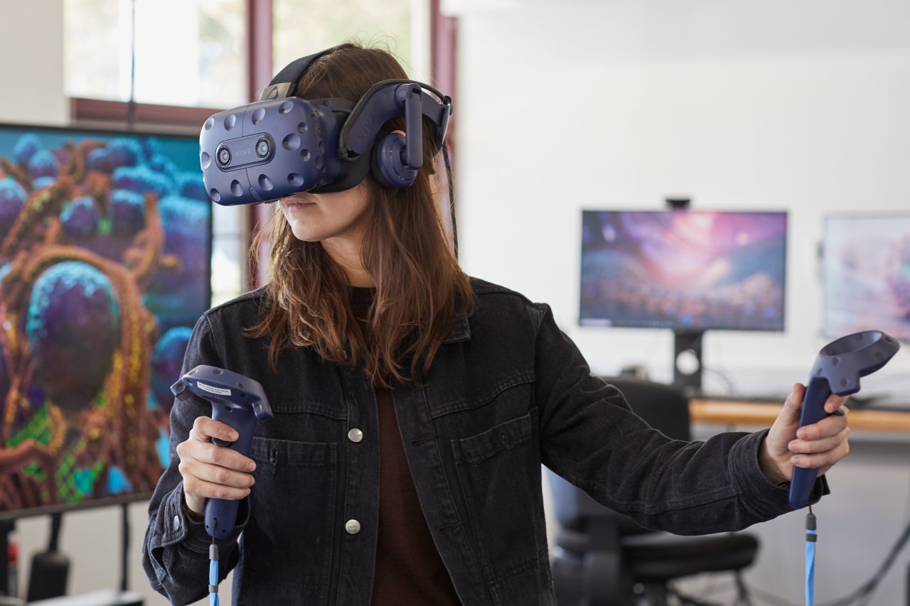 Student using virtual reality headset and controls in 3D Visualisation Aesthetics Lab.